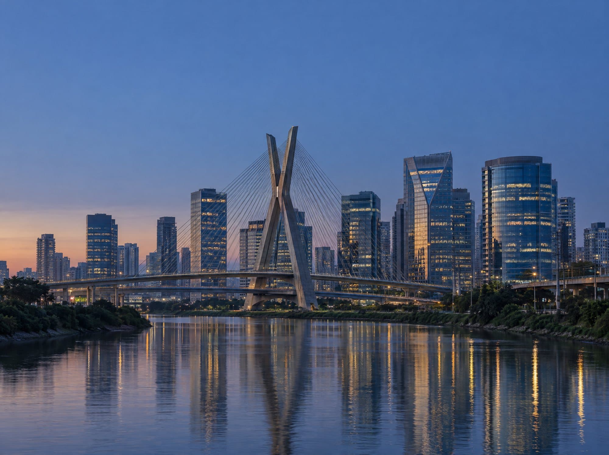 Região empresarial de São Paulo ao entardecer, com a Ponte Estaiada Octávio Frias de Oliveira sobre o Rio Pinheiros.